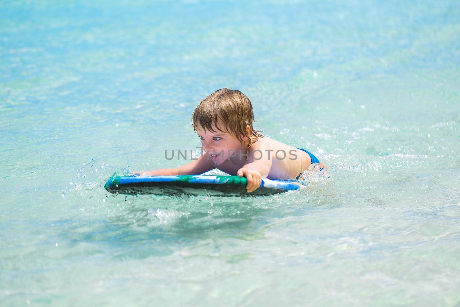 Young surfer, happy young boy in the ocean on surfboard