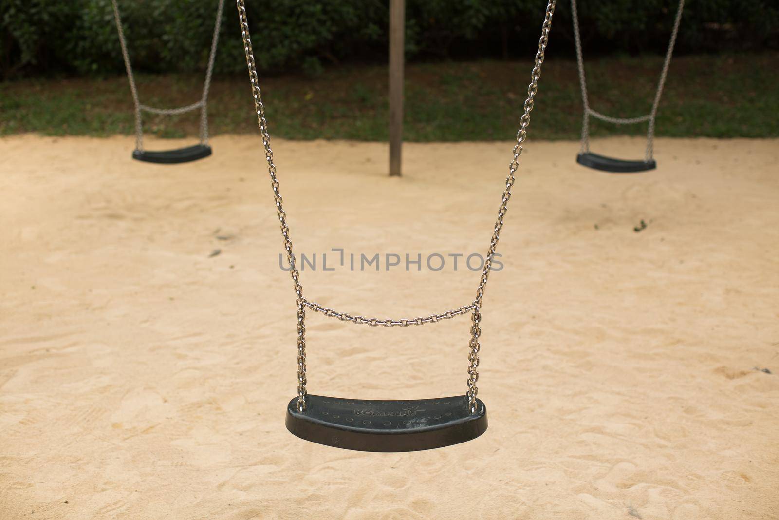 Swing set seat hanging on metal chains at a playground