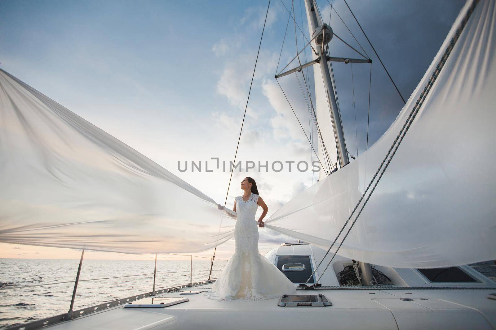 Happy bride on a yacht. White yacht with sail set goes along the island. by StudioPeace