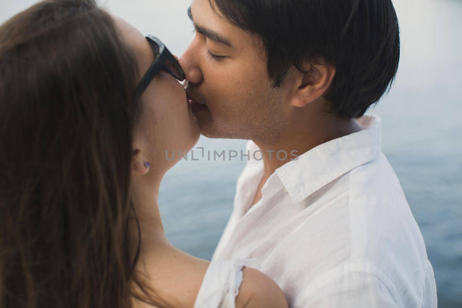 Young couple is traveling on a yacht in the Indian ocean. Man and a woman stand on the edge of the boat and kiss. by StudioPeace