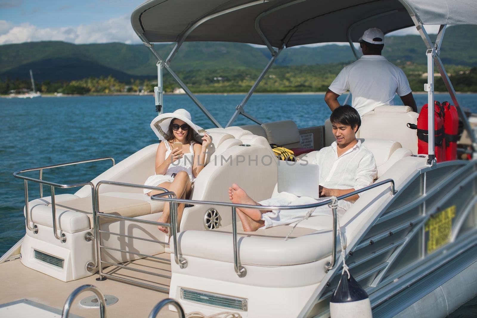 Handsome man and woman on deck of yacht with mobile phone and laptop. by StudioPeace