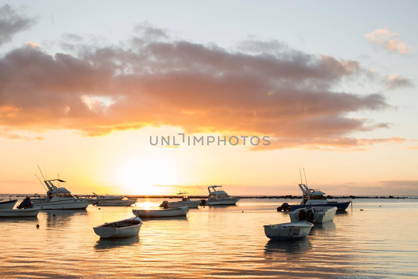 Small boats in the ocean at sunset.