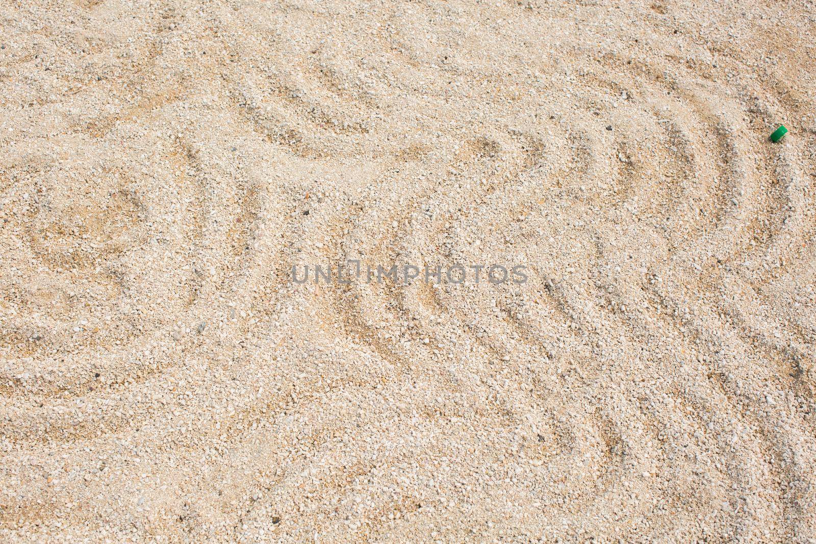 A pattern on the yellow sand of a round shape on the shore.