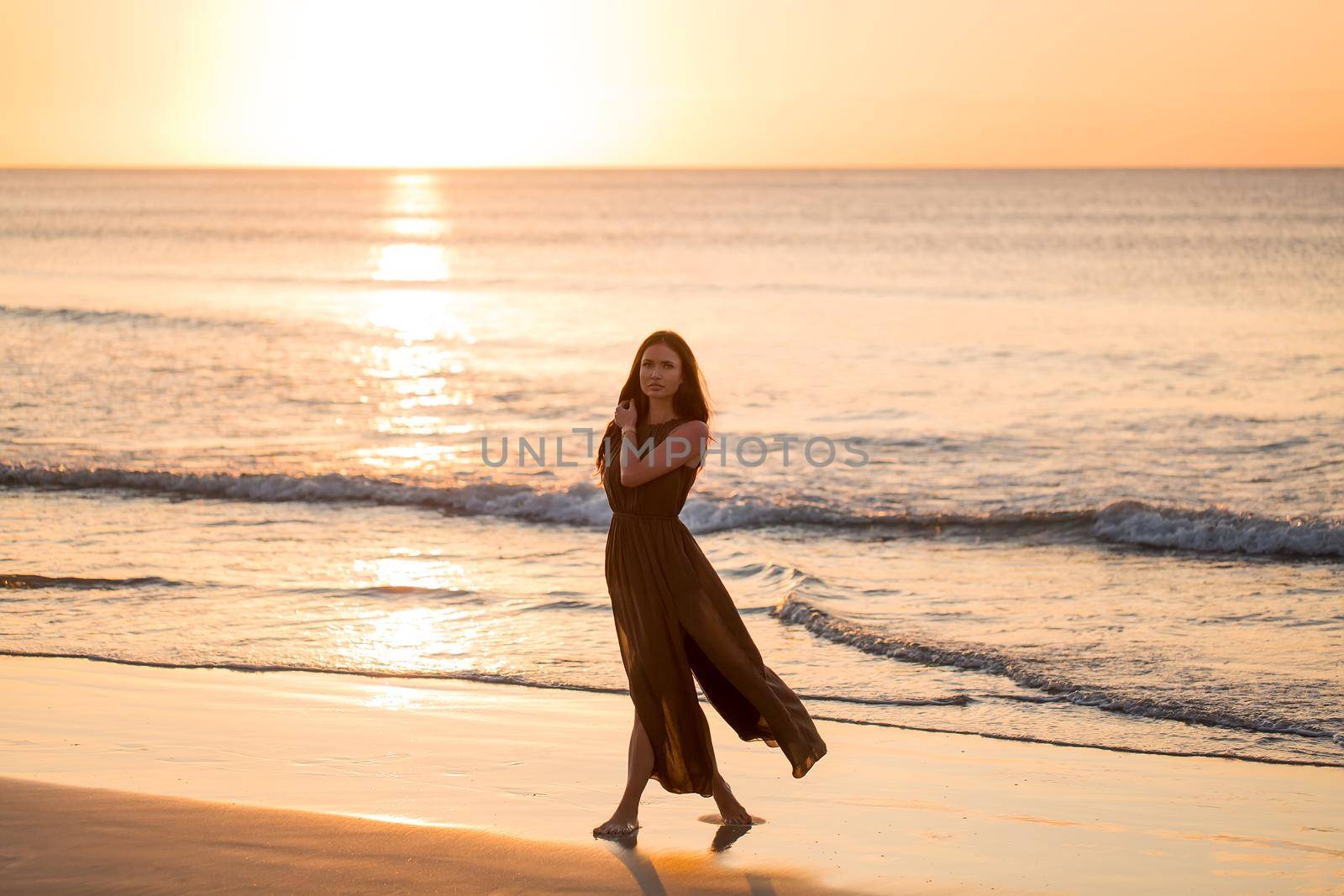 Beautiful woman on sunset background. Colorful dawn over the sea. Carefree woman enjoying the sunset on the beach. Happy lifestyle