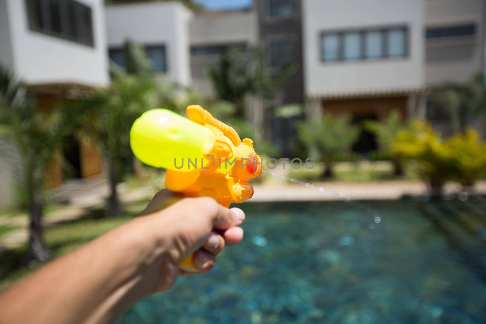 Man fires a water gun into a woman, while having fun in the pool by StudioPeace