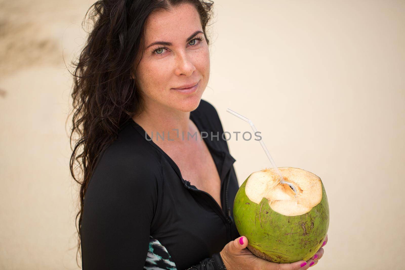 Portrait of a young woman with a coconut in her hands on the beach by StudioPeace