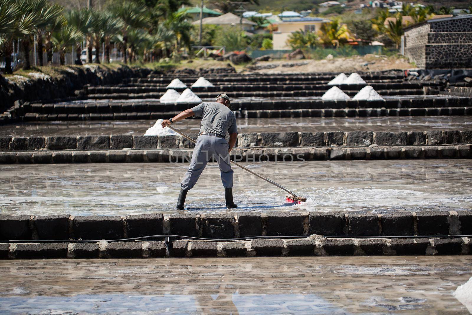 People collect the salt on a Sunny day on the shores of the Indian ocean in Mauritius by StudioPeace