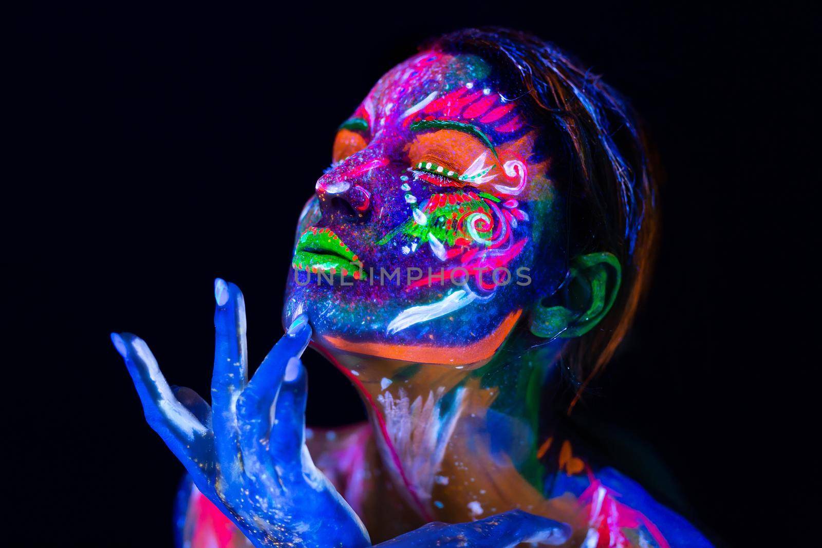 Body art glowing in ultraviolet light. Body art on the body and hand of a girl glowing in the ultraviolet light
