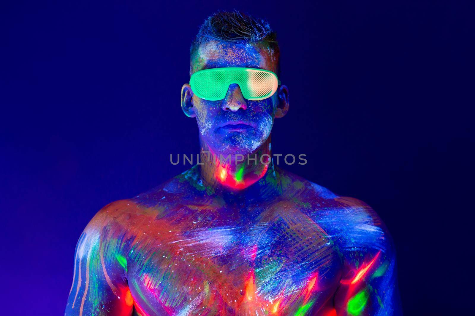 Portrait of a pumped-up man at a disco. Fluorescent paint on face in with UV light. by StudioPeace