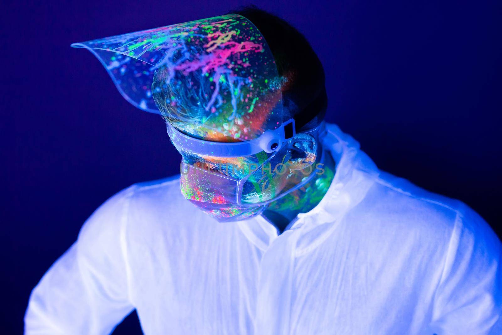 Portrait of man doctor in protective clothes in ultraviolet neon light during coronavirus pandemic. Epidemic, pandemic of coronavirus covid-19