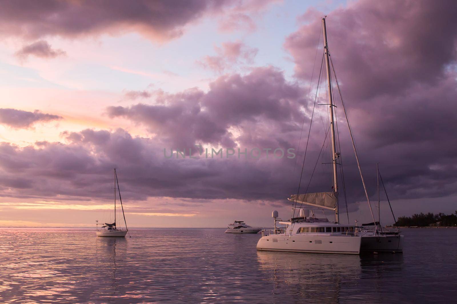 Catamaran yacht in the ocean at sunset.