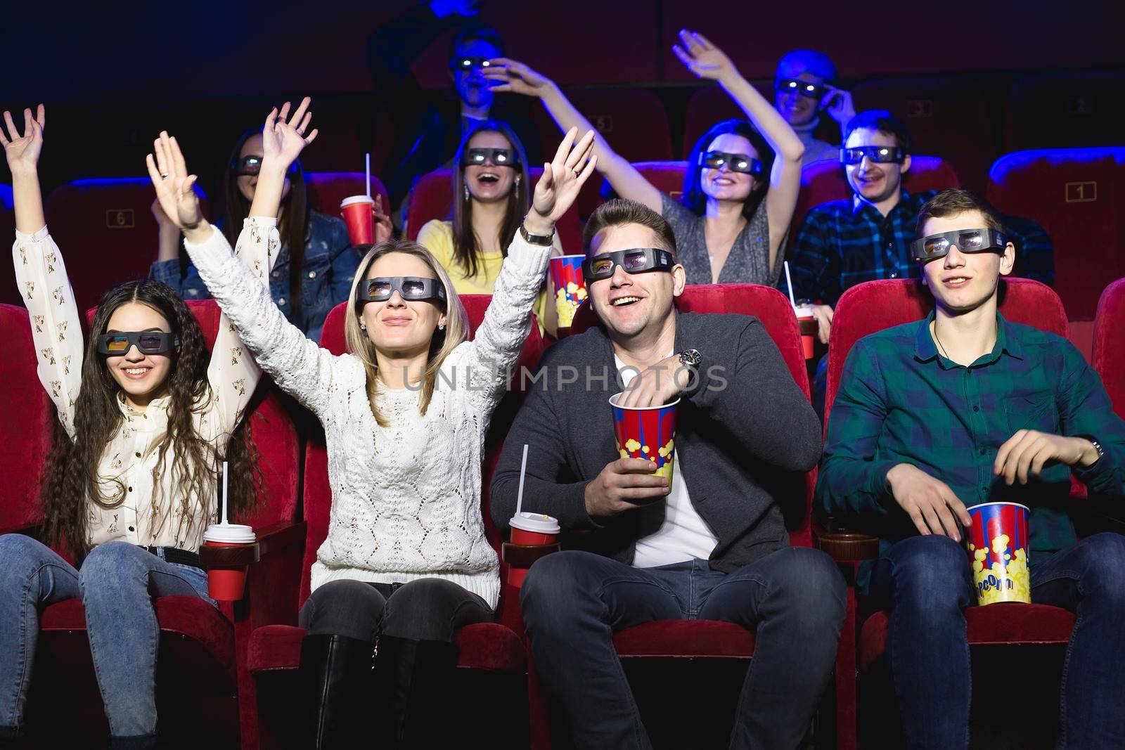 Friends in the cinema watch a funny movie with 3D glasses, laugh, have fun by StudioPeace