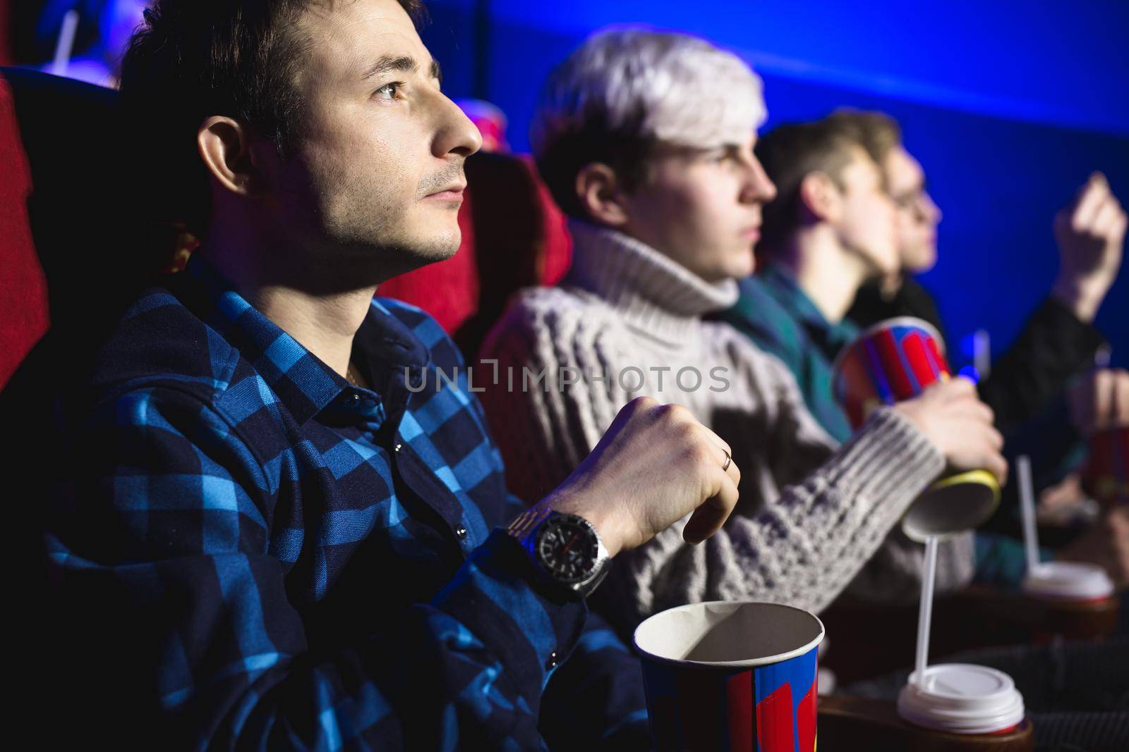 Young man eats popcorn in the cinema and watches a movie.