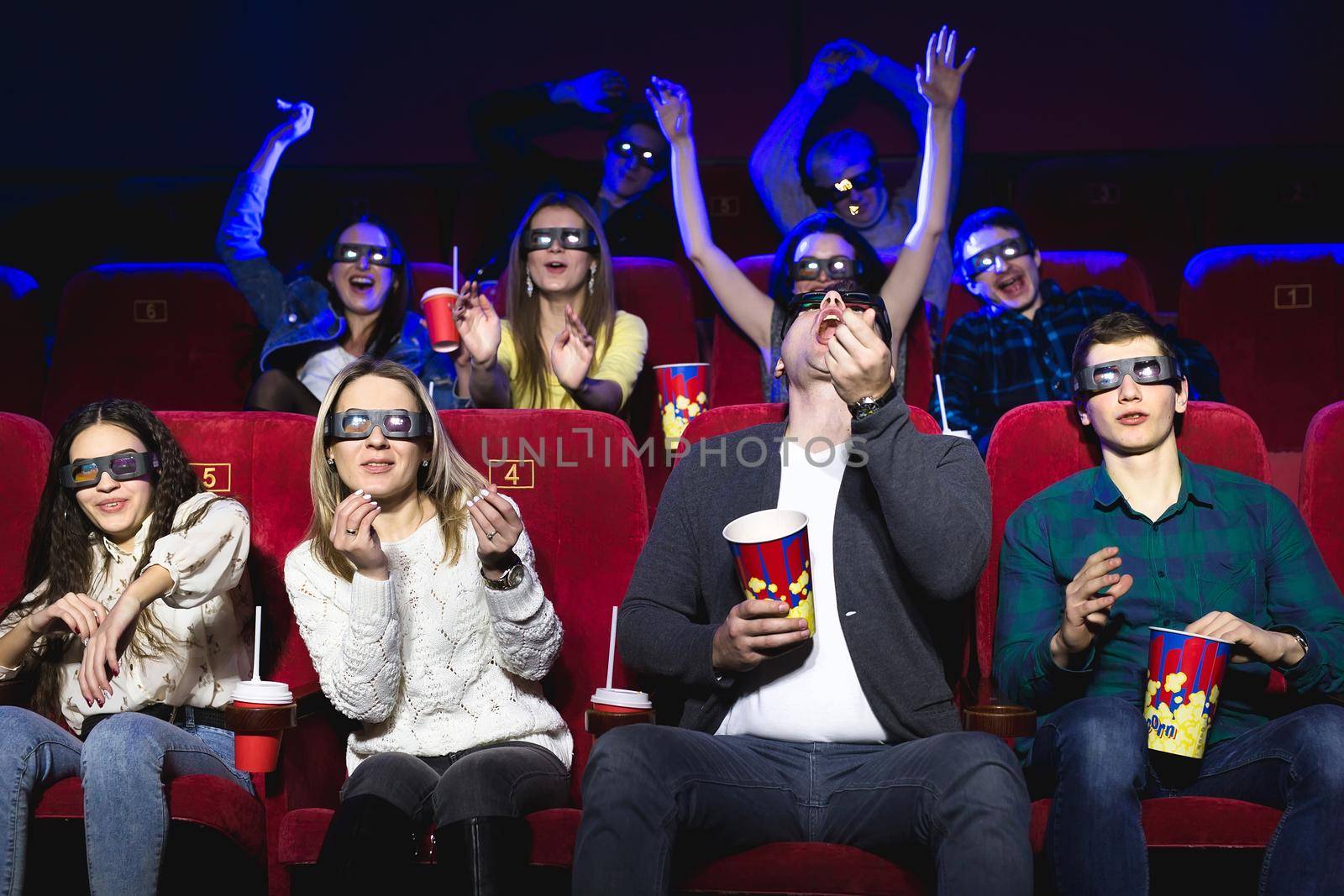 Friends in the cinema watch a funny movie with 3D glasses, laugh, have fun by StudioPeace