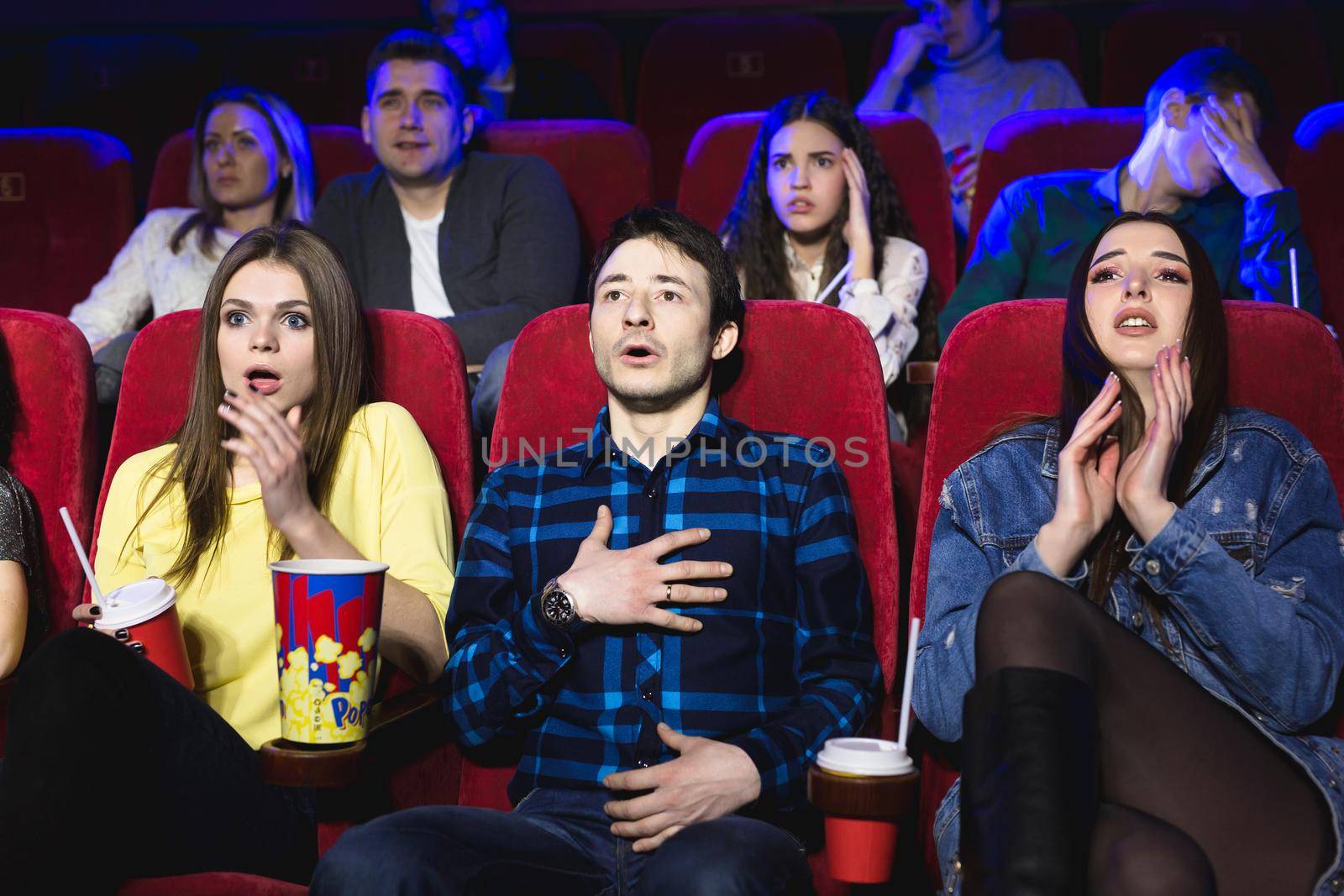 Group of people watch a horror movie at the cinema. by StudioPeace