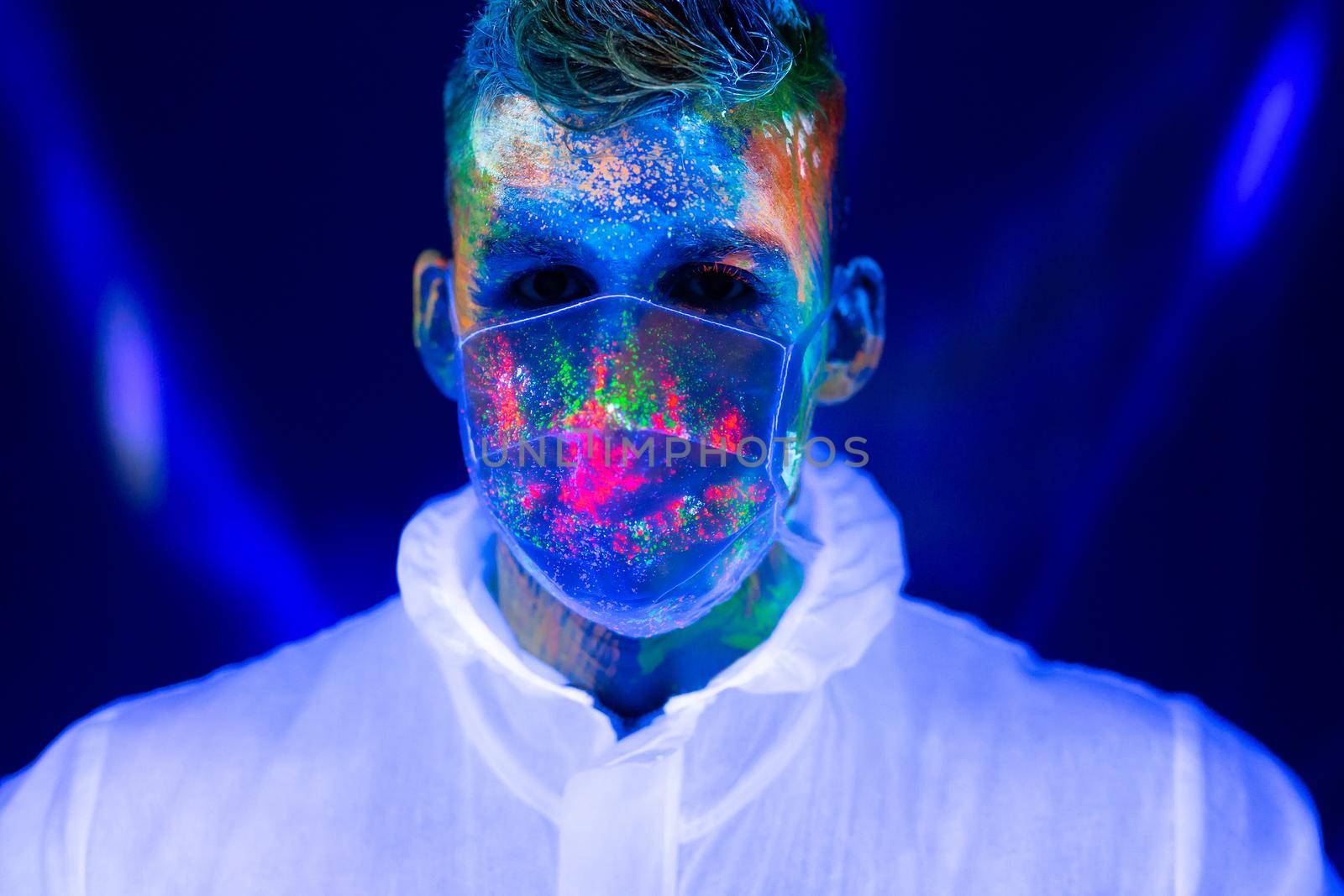 Portrait of man doctor in protective clothes in ultraviolet neon light during coronavirus pandemic. Epidemic, pandemic of coronavirus covid-19. by StudioPeace