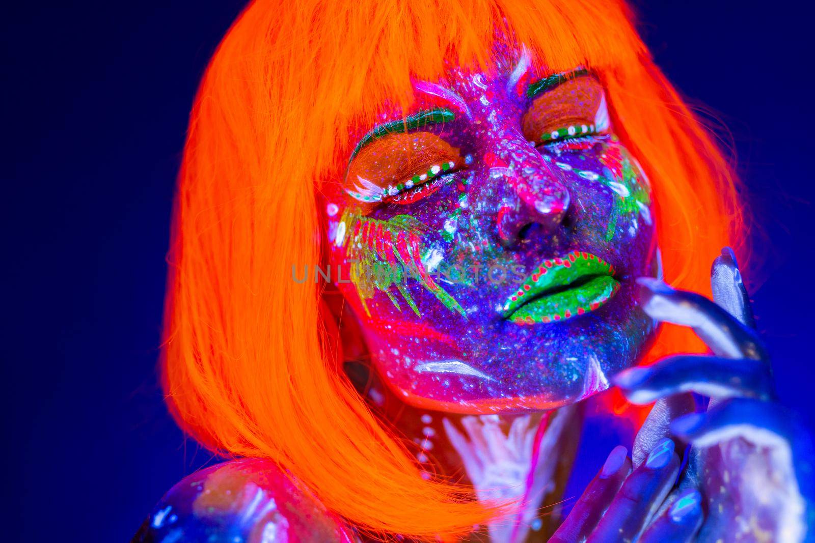 Portrait of woman in with neon makeup. Fluorescent paint in ultraviolet light