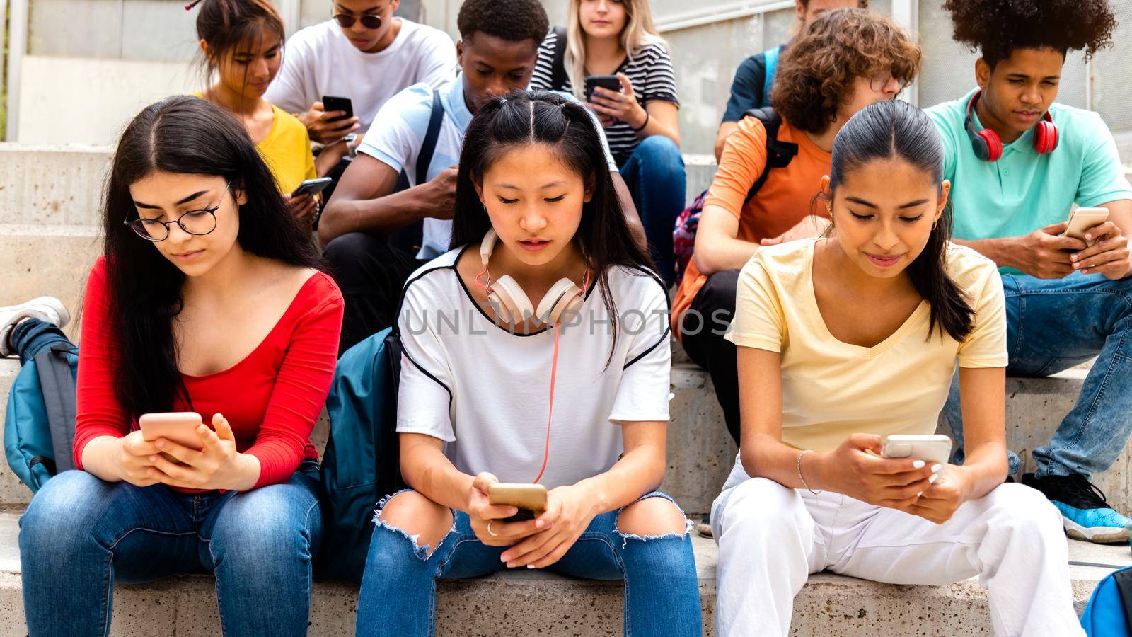 Group of multiracial high school students using mobile phone ignoring each other. Addicted to social media. by Hoverstock