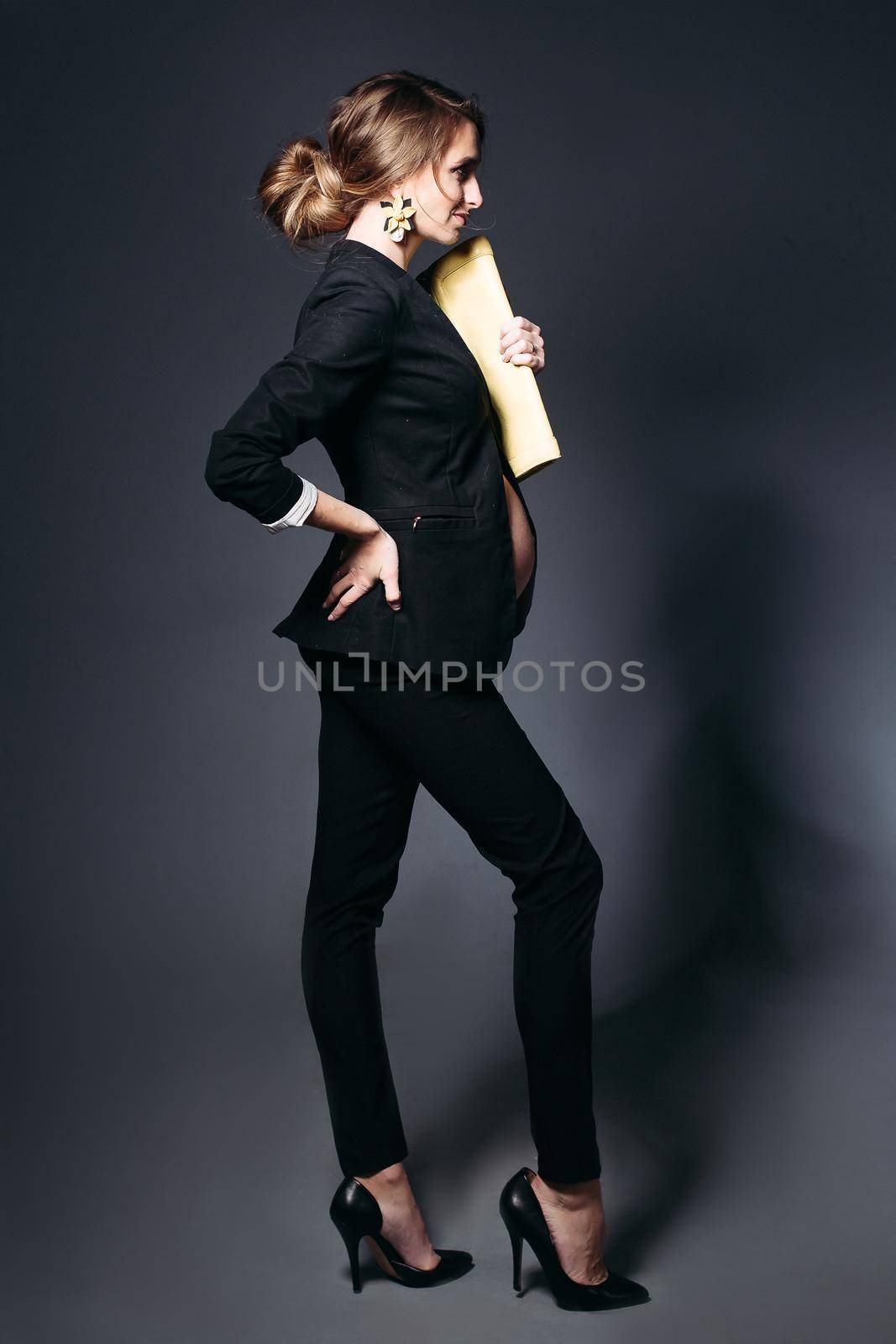 Portrait of fashionable pregnant woman wearing in black suit against black studio background. by StudioLucky