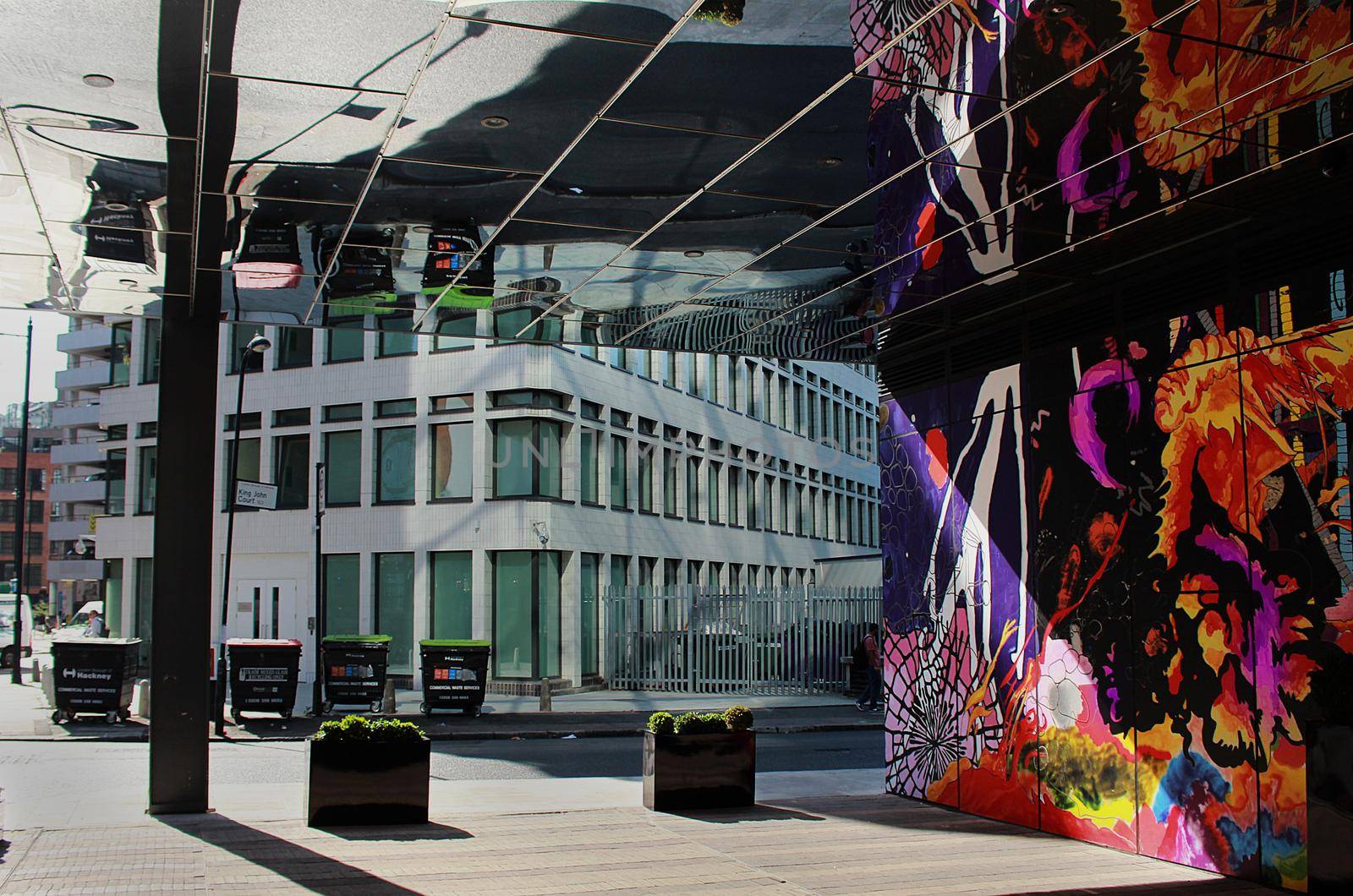 Graffiti artwork reflection on a mirrored building in a street in central London, UK. High quality photo.