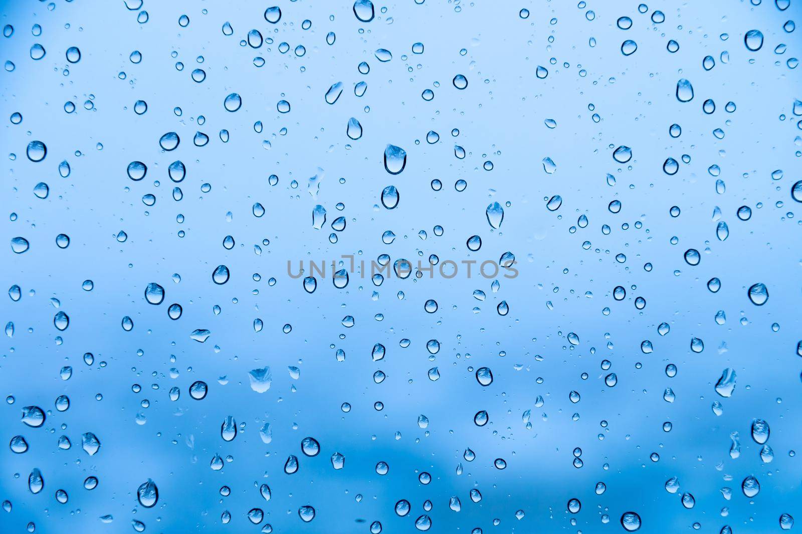 Water drops on glass natural bright blue background. Humidity background.
