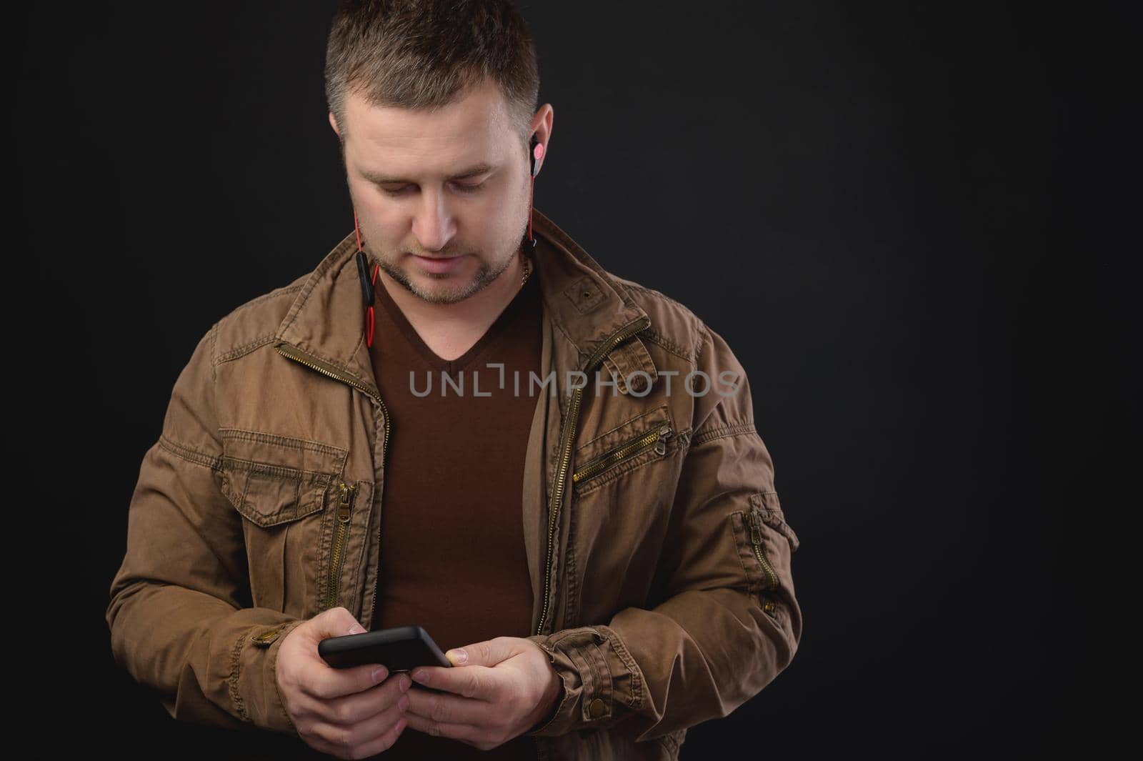 Middle aged Caucasian man uses telephone while standing in studio. Portrait of a freelancer surfing the internet.