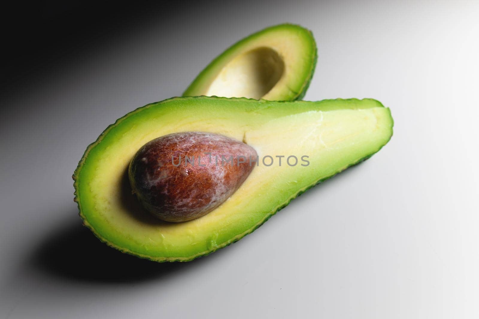Fresh vegetables - Zutano avocado on a white table with a black background. Contrasting image of a tasty vegetable.