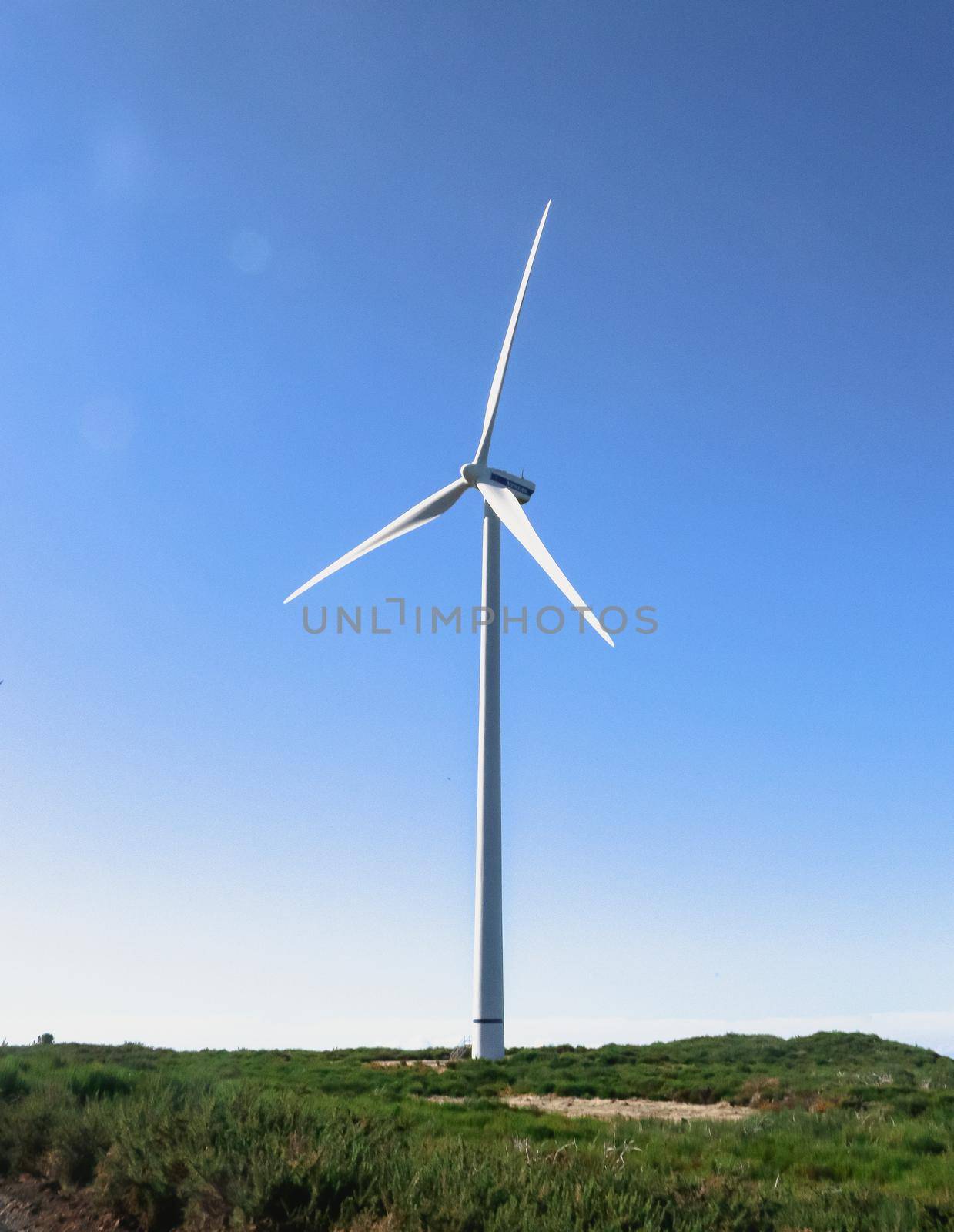 Lone wind turbine in front of a blue sky at the peak of a windy mountain in Santana, Madeira island, Portugal. High quality photo.