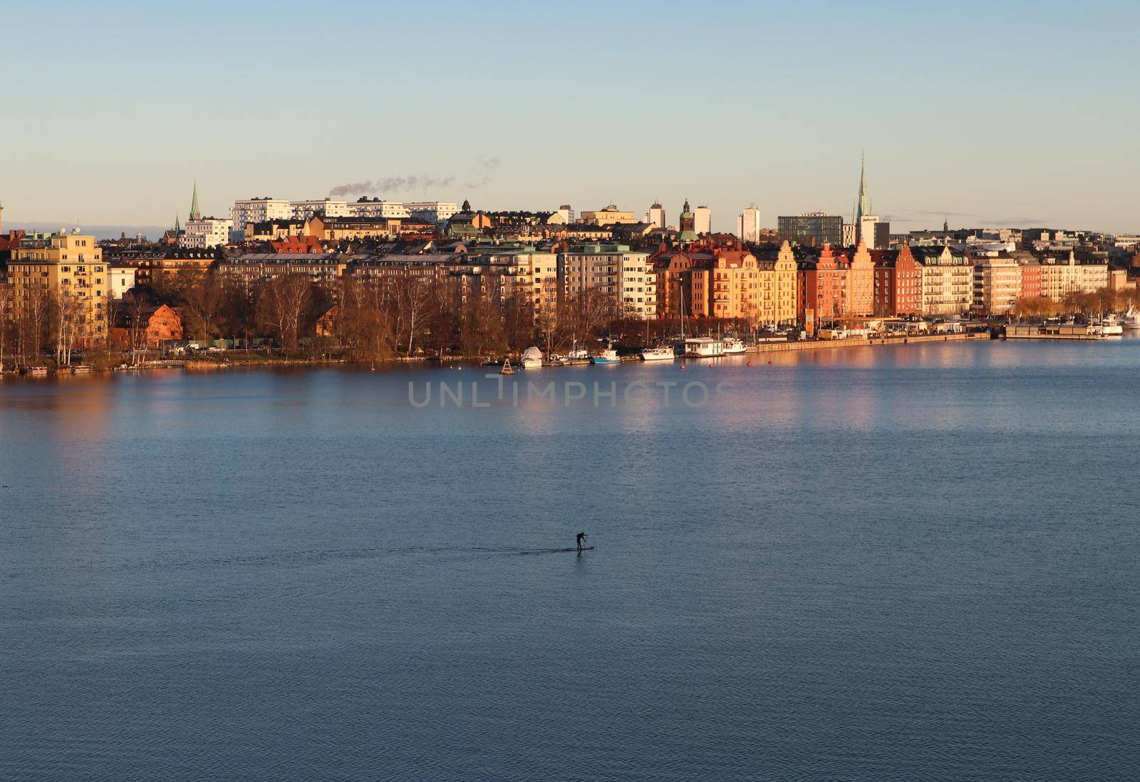 Lone paddle-boarder traversing the Stockholm archipelago at sunset, Stockholm, Sweden. by olifrenchphoto