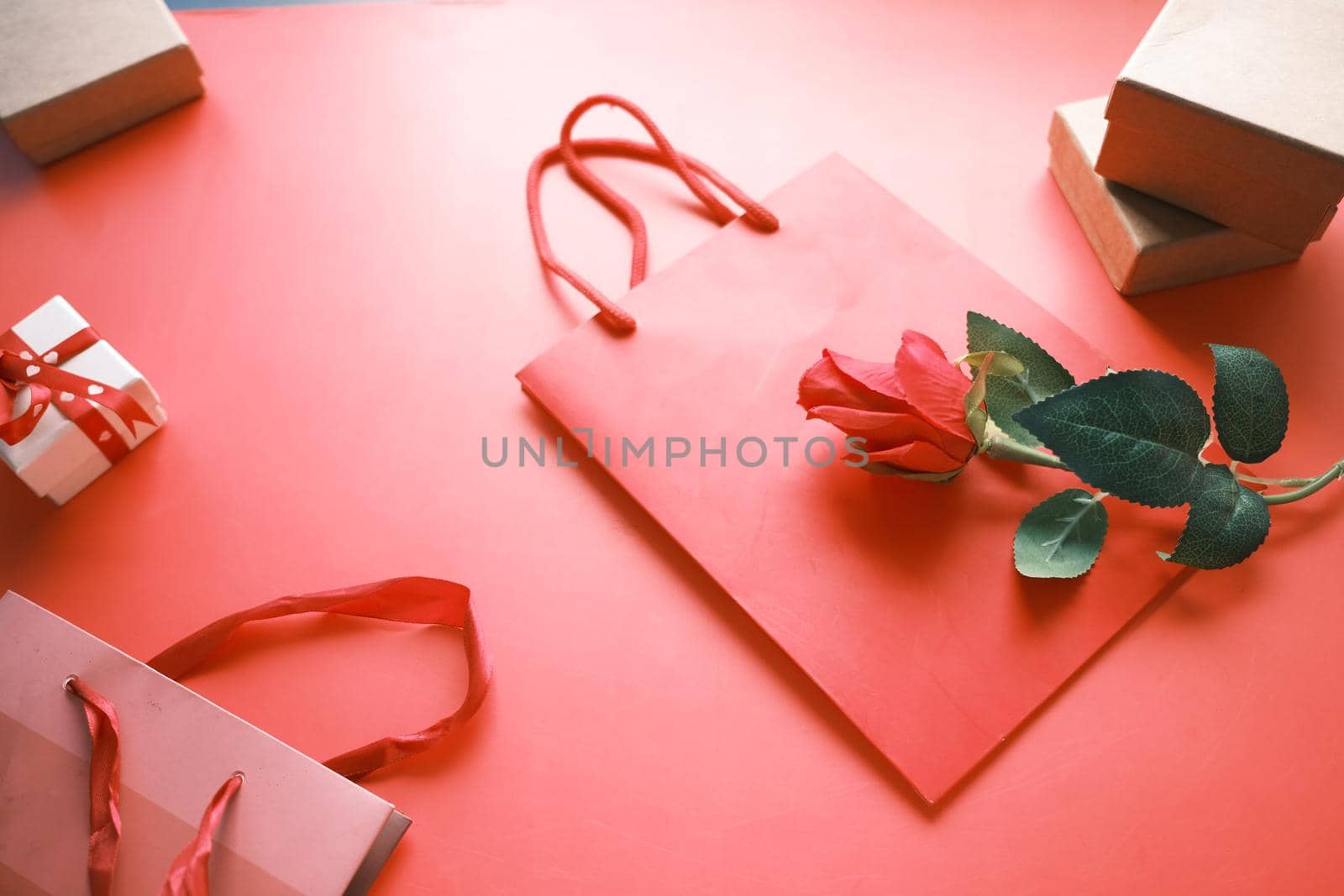 Top view of gift box and rose flower on red background .