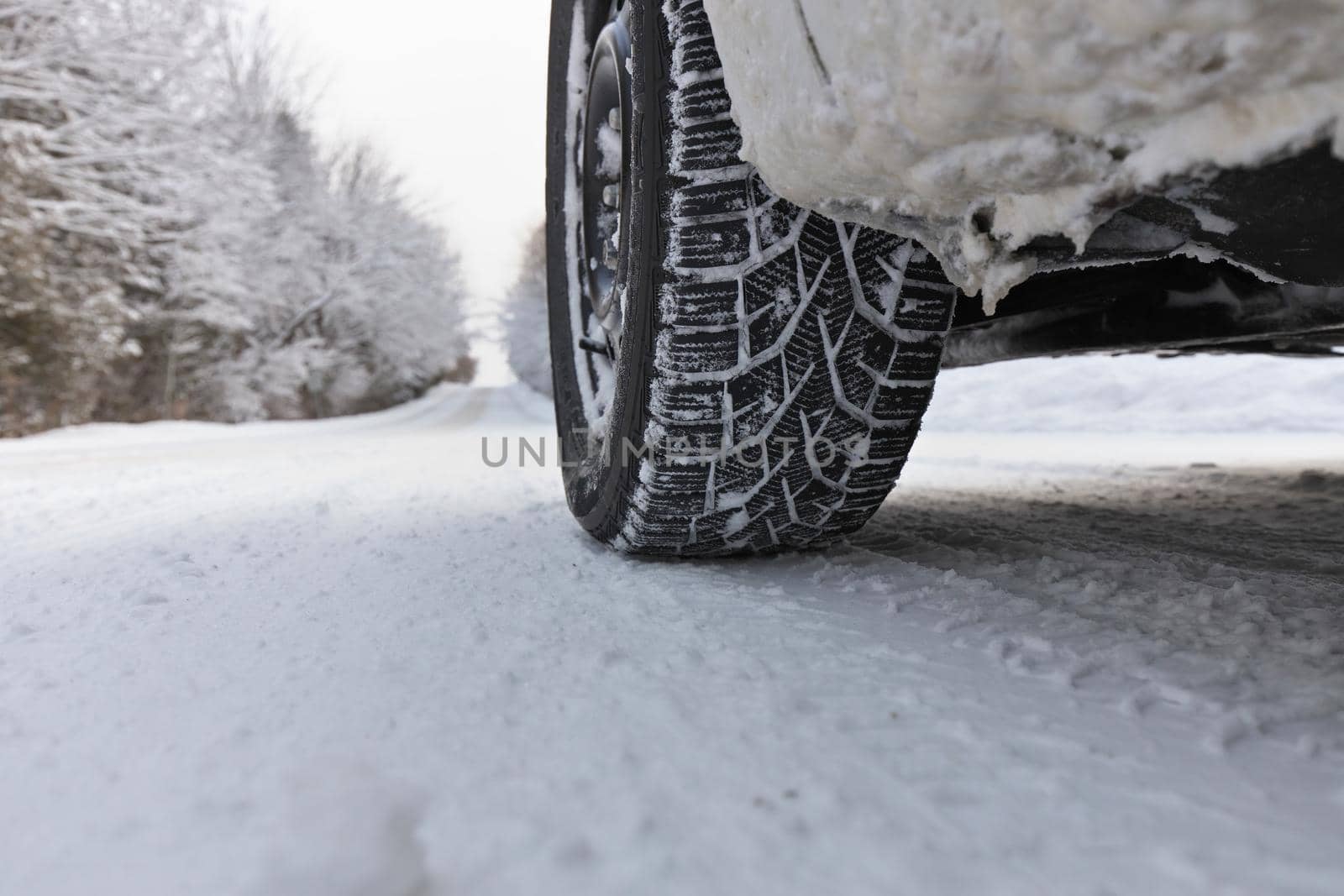 Close up of Winter Tire on Snow and Ice Covered Road on a country road. Plenty of copy space. High quality photo