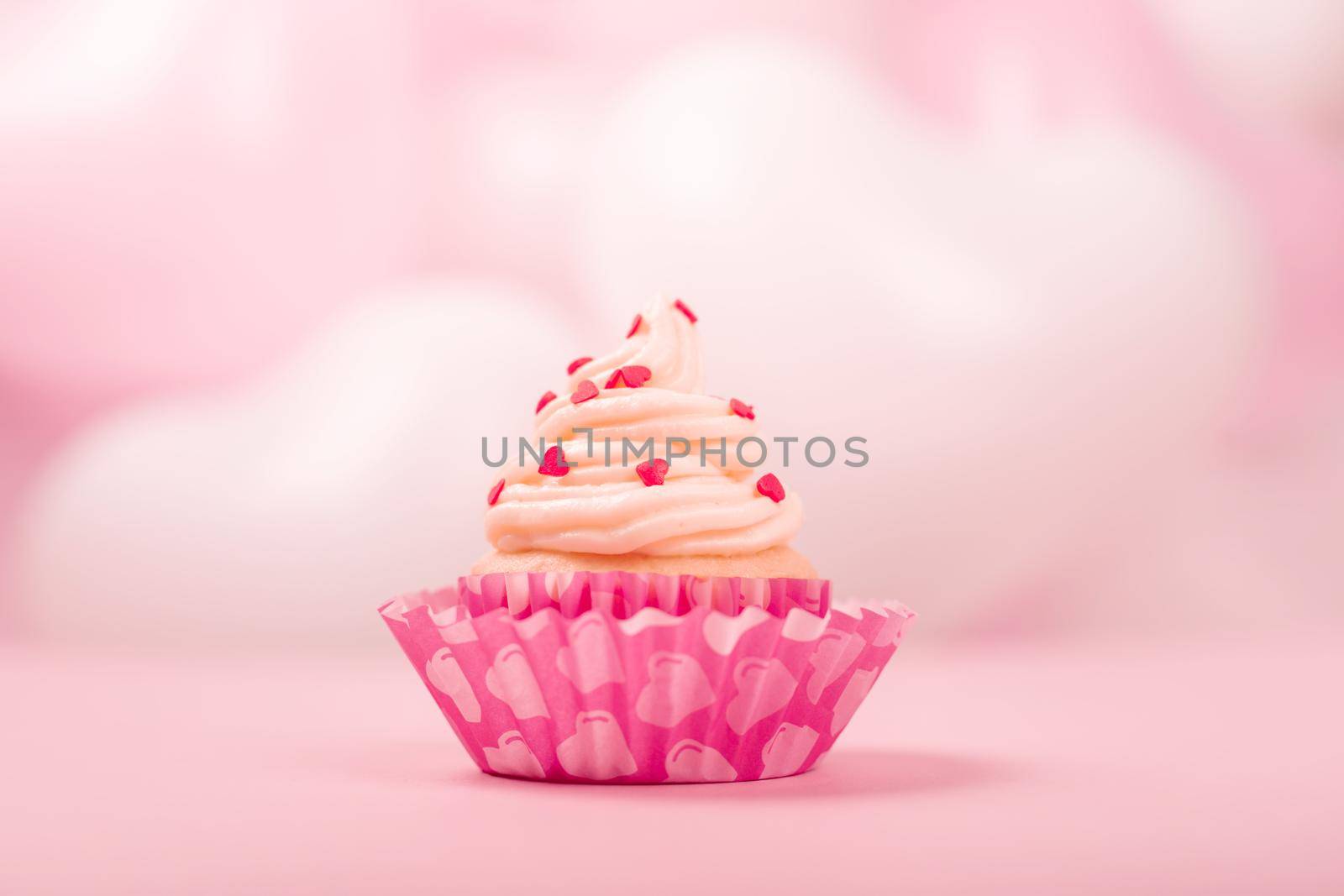 Valentine day love cupcake decorated with cream on pink and white party heart balloons background with copy space for text