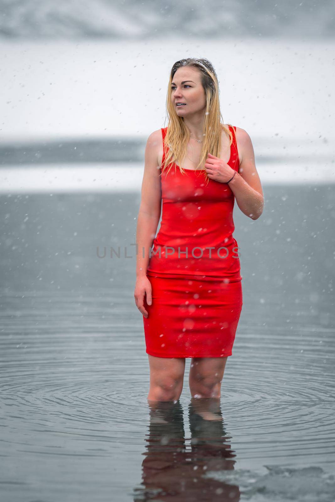 young beautiful woman in red dress by the snowy frozen lake in winter.