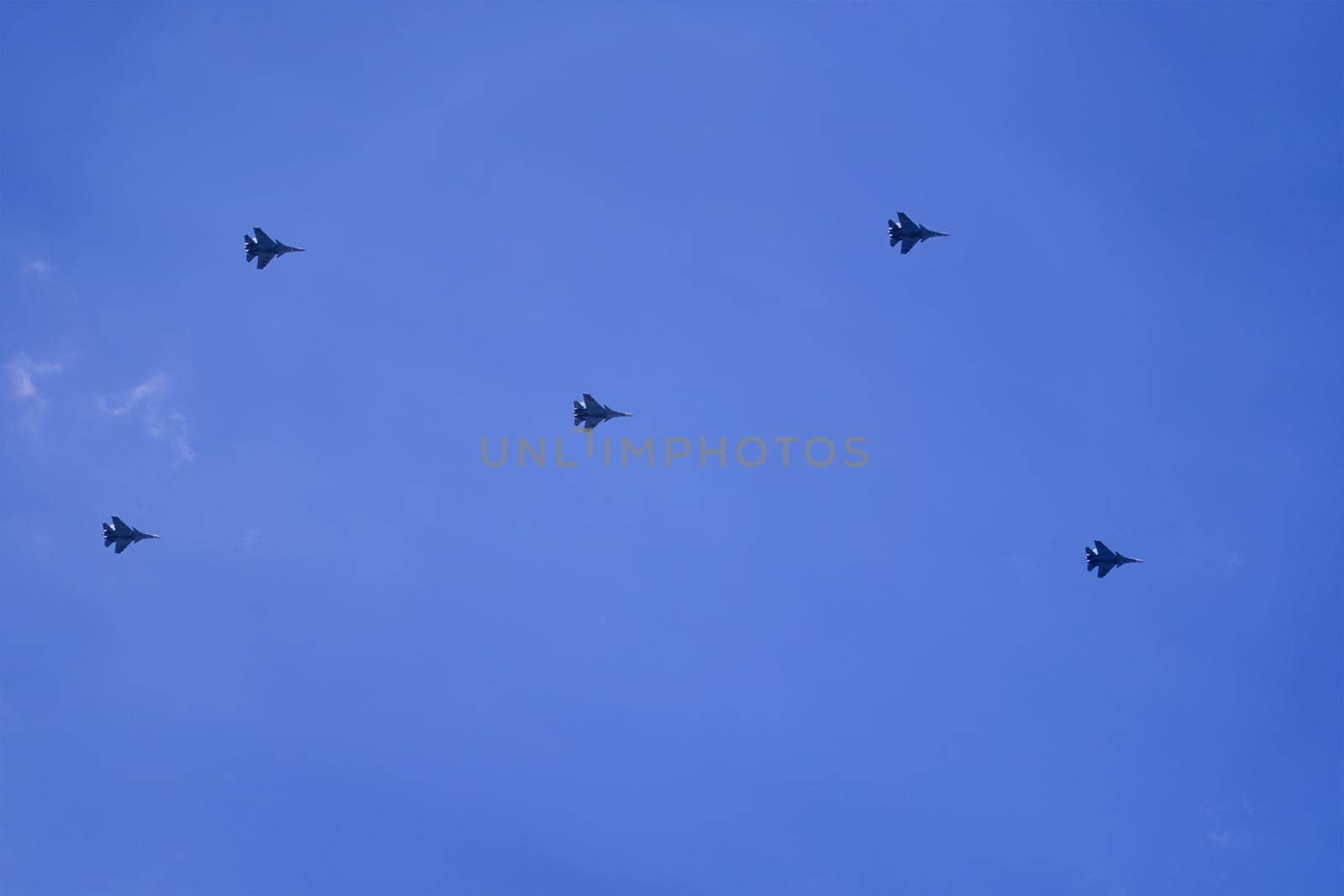 Group of military aircraft shows aerobatics in blue sky. Victory parade of army air force over the city. Representation of aviation equipment.