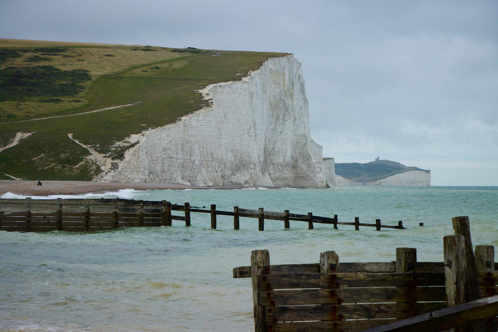 Dramatic view of the Seven Sisters coastline, sea and clouds with structures made of planks of wood. Taken in summer, England, UK on Canon EOS 90D.
