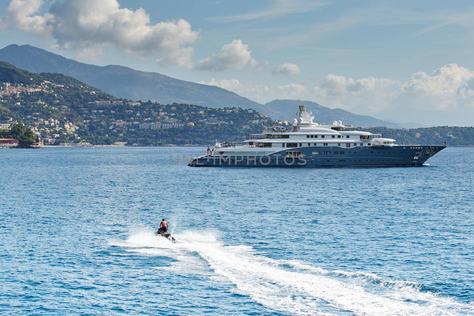 Monaco, Monte-Carlo, most expensive mega yacht on sea, sunny day, Jet Ski, mountains on background. High quality photo