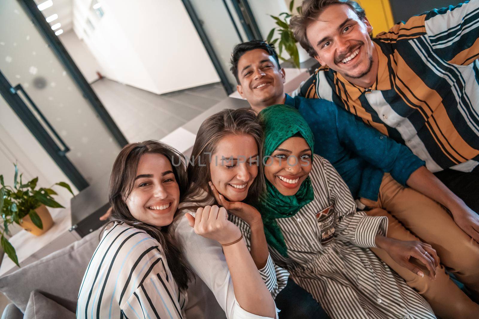 Group of business people during break from the work taking selfie picture while enjoying free time in relaxation area at modern open plan startup office. Selective focus by dotshock