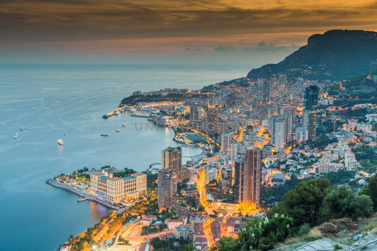 Aerial view of Monaco - Monte-Carlo at dusk, cityscape with night illumination, mountain, skyscrapers, mediterranean sea. High quality photo