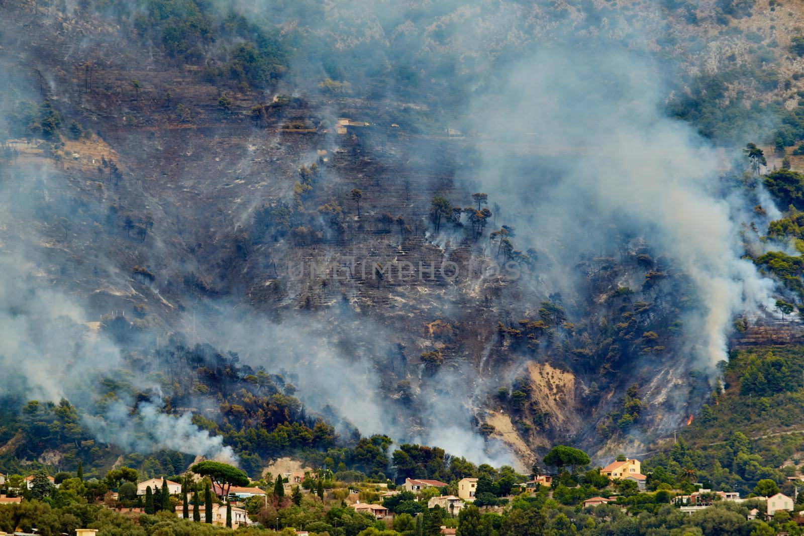 Fire in the forest mountain in the Italian town of Ventimiglia, all the mountains in the smoke, the villa is on fire, the fire service aircraft extinguish a fire. High quality photo
