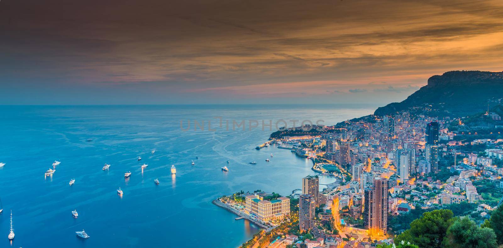A lot of yachts and motor boats with night illumination are moored in mediterranean sea, aerial view of bay of Monaco - Monte-Carlo at dusk, cityscape with night illumination by vladimirdrozdin
