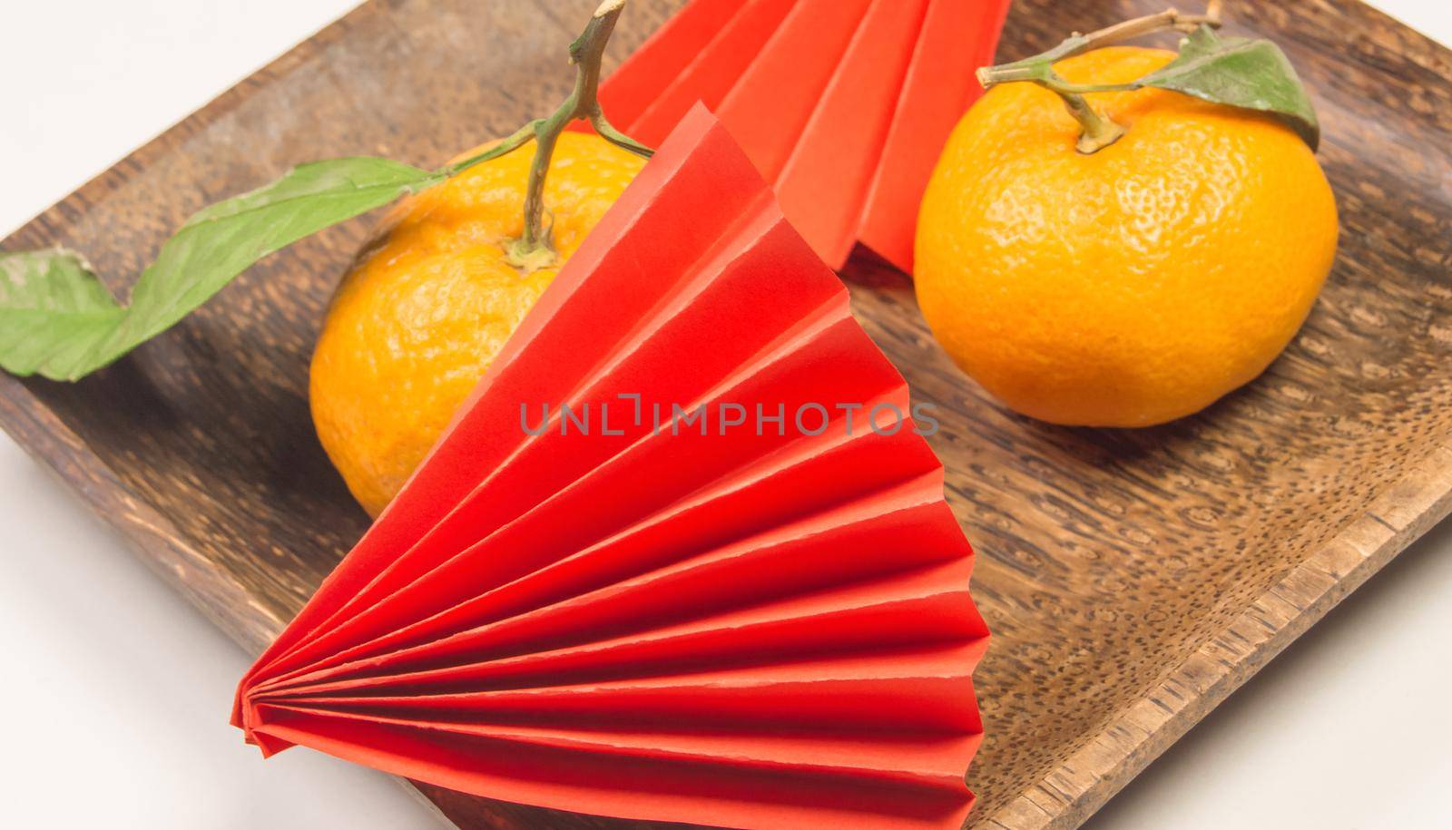 Chinese New Year, composition with tangerines, funny origami made of red paper on a dark wooden plate on a white background by claire_lucia