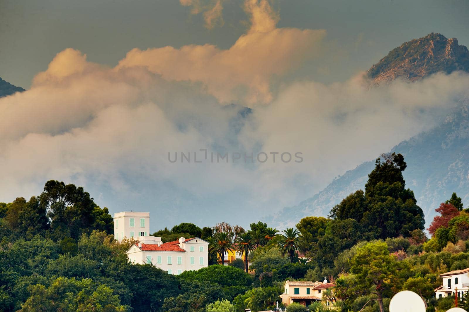 View of the mountains of Italy at sunset, Ventimiglia at sunset through the villa and forest, orange and pink clouds. High quality photo