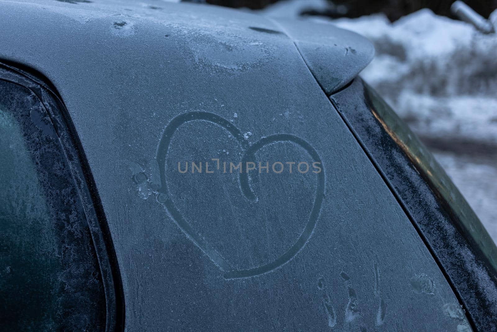 heart symbol on frozen grey car body in winter. High quality photo