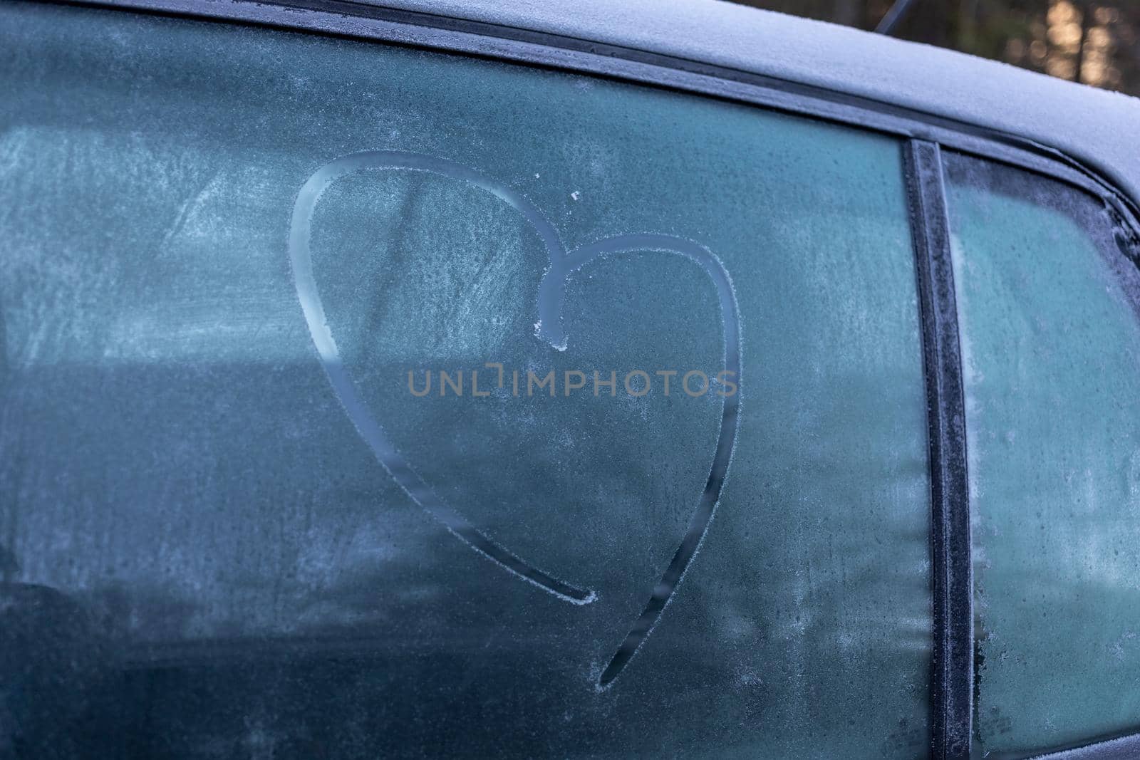 heart symbol on frozen grey car window in winter by Chechotkin