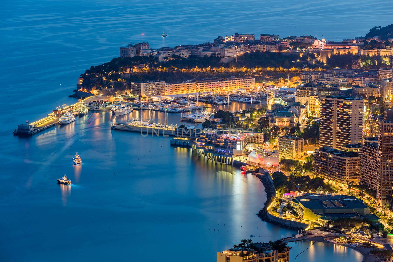 Aerial view of Monaco - Monte-Carlo at dusk, cityscape with night illumination, mountain, skyscrapers, mediterranean sea. High quality photo