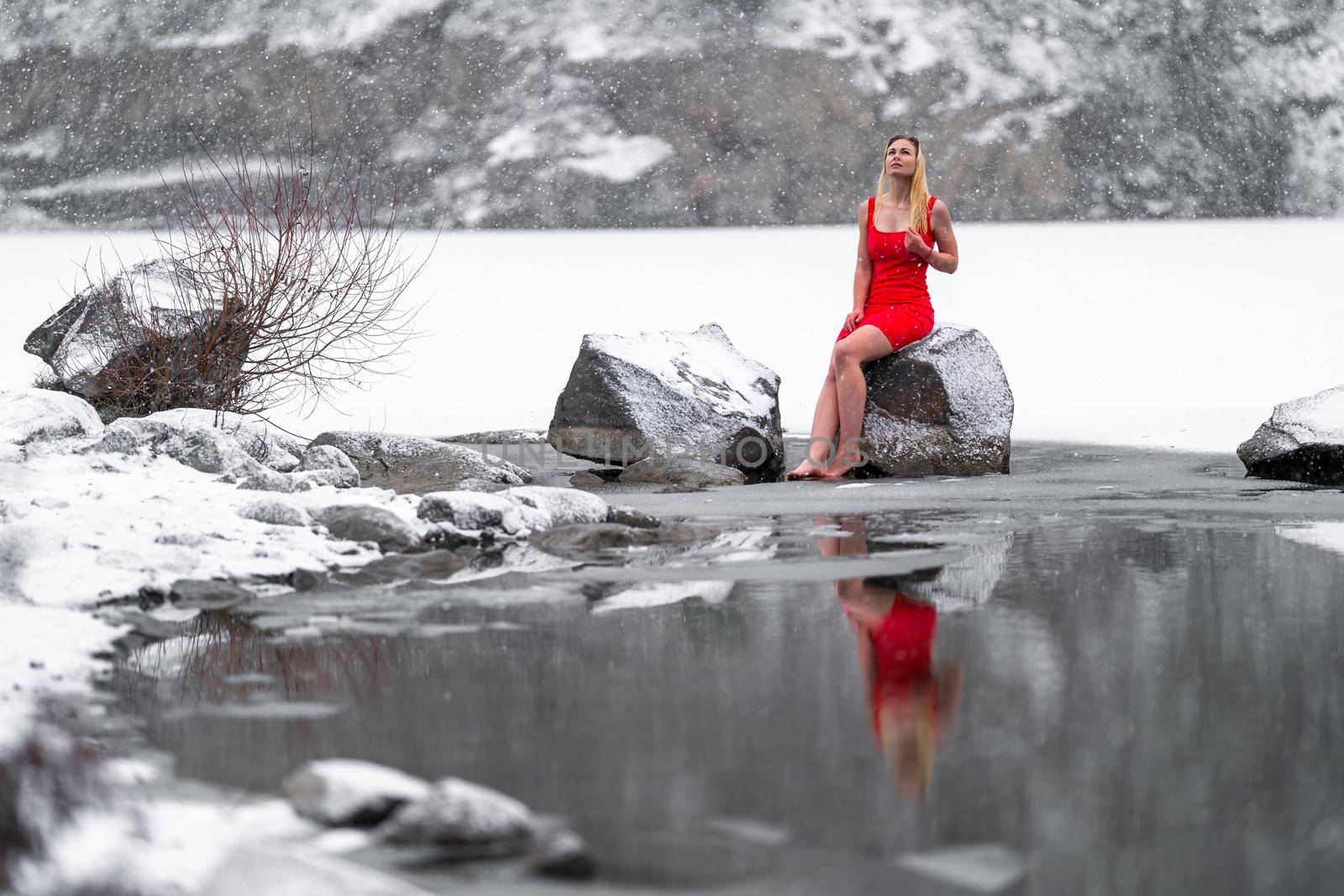 young beautiful woman in red dress by the snowy frozen lake in winter by Edophoto