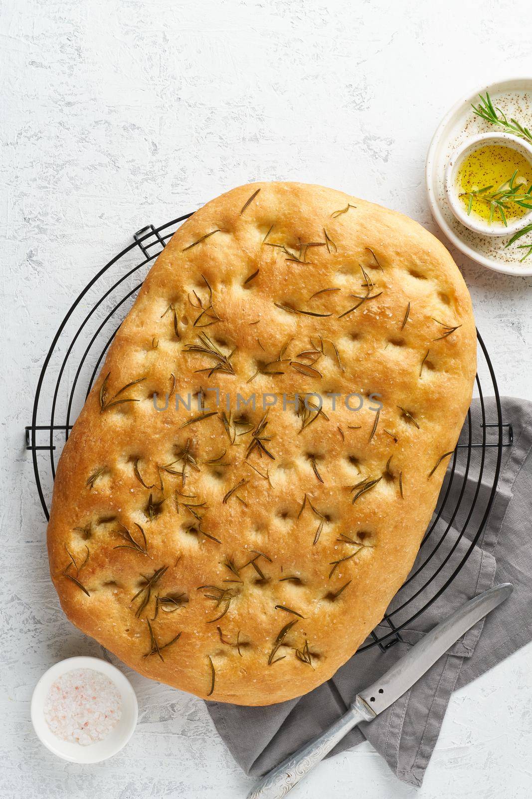 Focaccia, pizza, italian flat bread with rosemary and olive oil on grid by NataBene