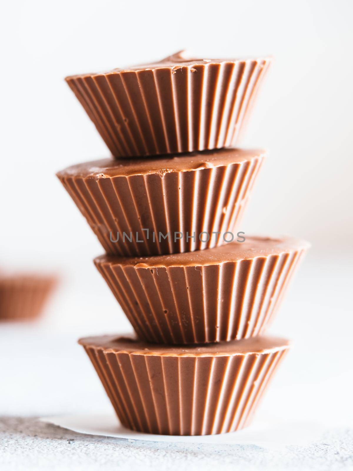 Stack of vegan chocolate cups with caramel on white tabletop. Homemade vegetarian chocolate caramel cups. Ideas and recipes for healthy sweets and dessert. Selective focus, Shallow DOF.