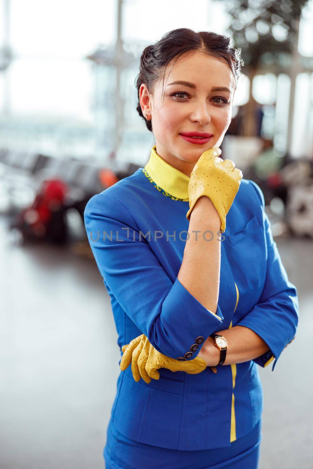 Female flight attendant standing in airport terminal by Yaroslav_astakhov