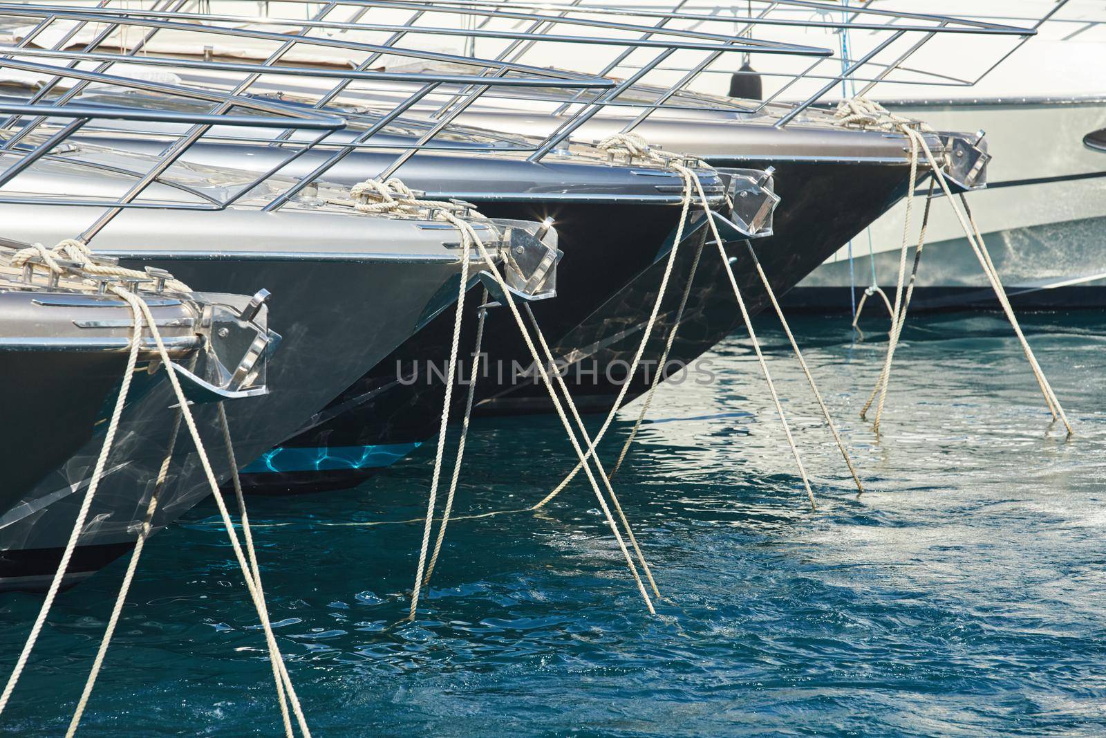 Monaco, Monte-Carlo, a lot o motor boats are moored in port at sunny day, mooring ropes go into the azure water, prows of motor boats in a row, boat railings . High quality photo